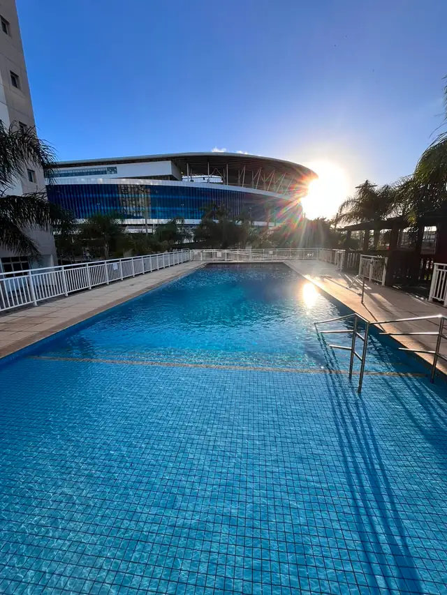 Piscina de condomínio com vista para a arena, água cristalina ao entardecer
