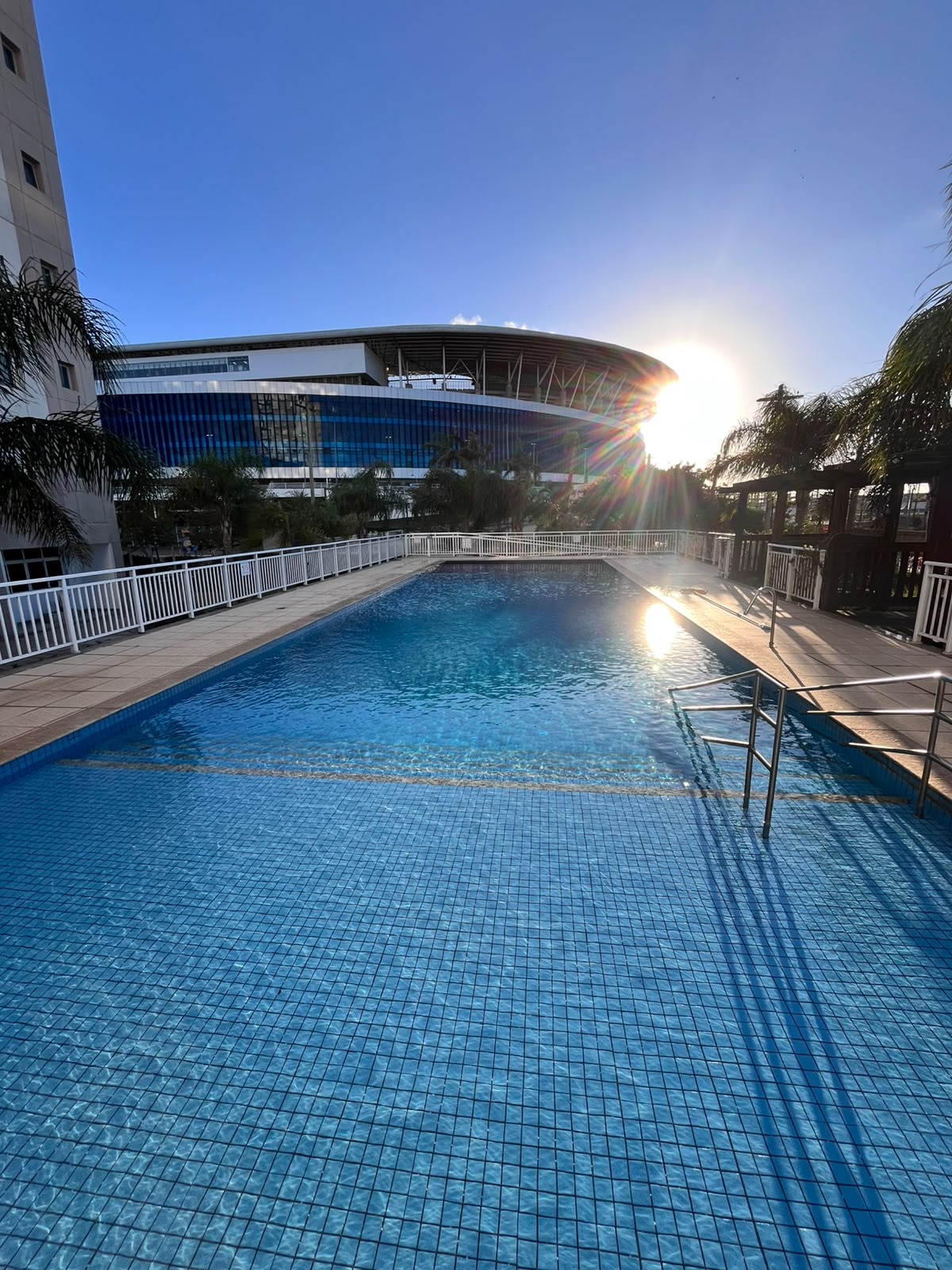 Piscina de condomínio com vista para a arena, água cristalina ao entardecer